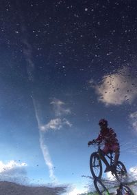 Low angle view of biker against blue sky at night