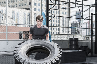 Man training at rooftop gym in bangkok with tractor tyre