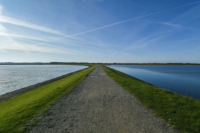 Road amidst field against sky