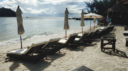 Chairs on beach against sky