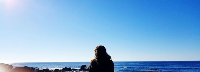 Woman looking at sea against clear sky