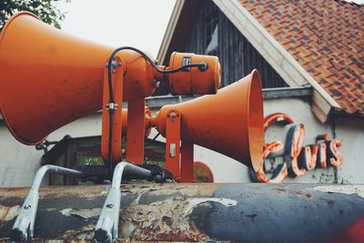 Close-up of orange megaphones against building