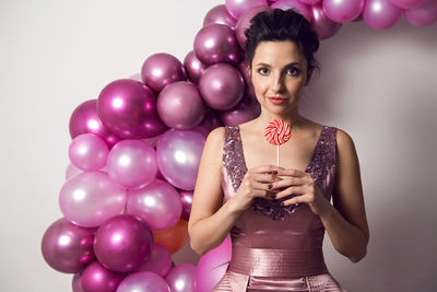 Girl in pink dress holding round striped candy