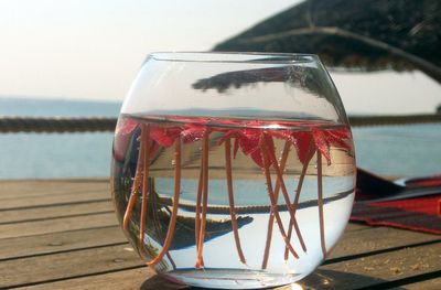 Close-up of drink on table at beach against sky
