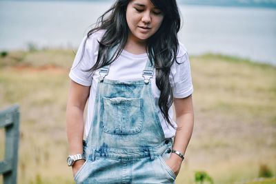 Beautiful young woman standing against lake