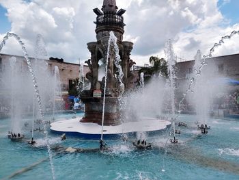 Fountain in swimming pool by sea against sky