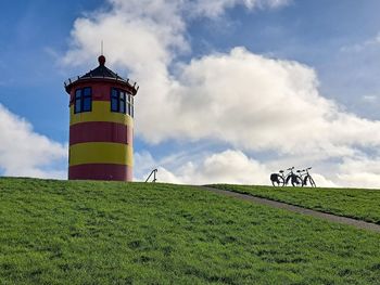 Lighthouse on field against sky