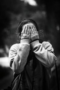 Woman covering her face with hands while standing outdoors