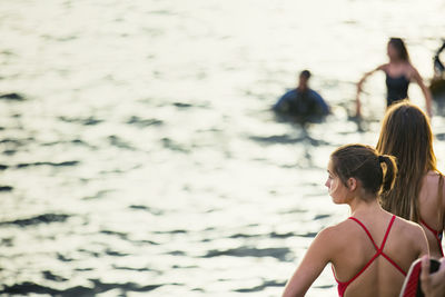 Rear view of women standing at beach