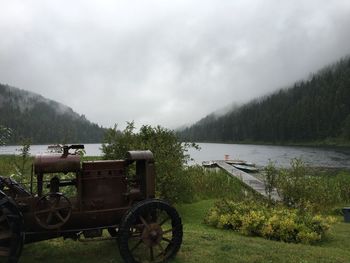 Bicycle on field by lake against sky