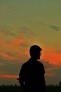 Silhouette man standing against orange sky