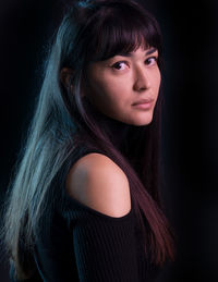 Side view portrait of woman with long hair against black background