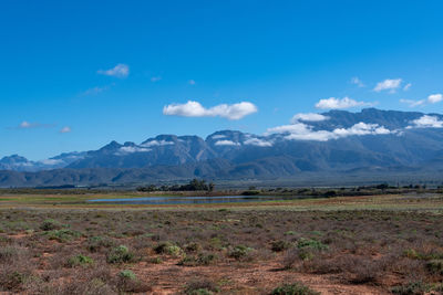 Scenic view of field and mountains against blue sky