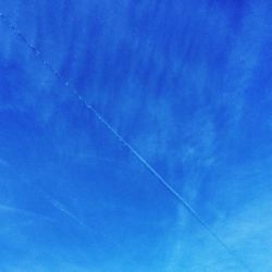 Low angle view of vapor trails in blue sky