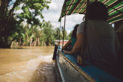 Rear view of woman sitting in boat on river