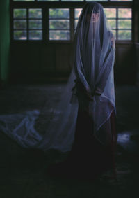 Woman seen through netting while standing on floor in darkroom