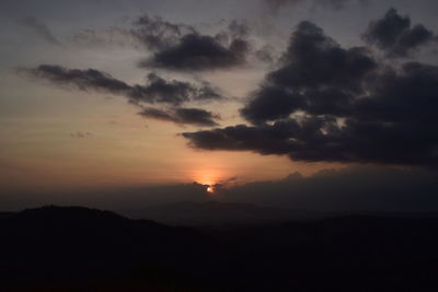 Scenic view of silhouette mountain against dramatic sky during sunset