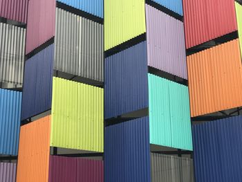 Multi colored chairs on pier against blue sky