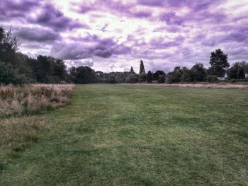 Scenic view of grassy field against cloudy sky