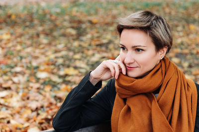 A brooding short-haired woman in autumn in a terracotta scarf