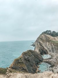 Rock formations by sea against sky