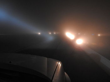 Illuminated car on street against sky at night