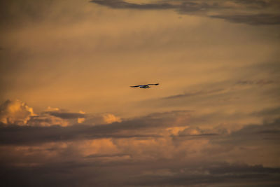 Silhouette airplane flying against sky at sunset