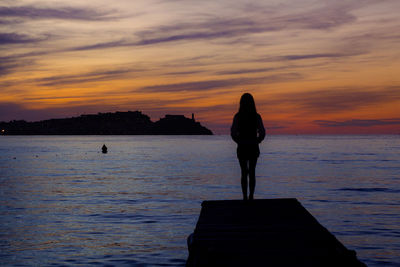 Silhouette woman standing on pier against sky during sunset