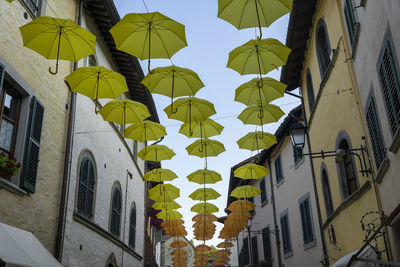 Low angle view of umbrellas hanging by building against sky