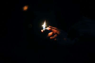 Cropped hand of person lighting sparkler during night