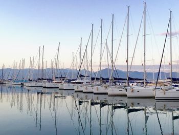 Sailboats moored in harbor against clear blue sky