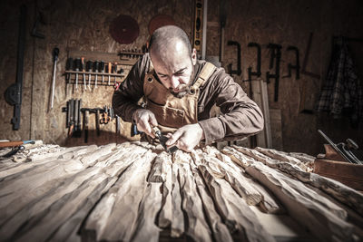 Man carving wood on table at workshop