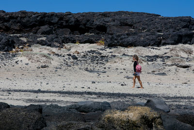 Woman standing on rock against sky