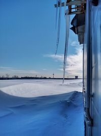 Snow covered landscape against blue sky