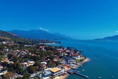 High angle view of townscape by sea against blue sky