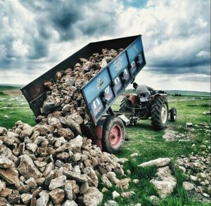 Stack of logs on land against sky