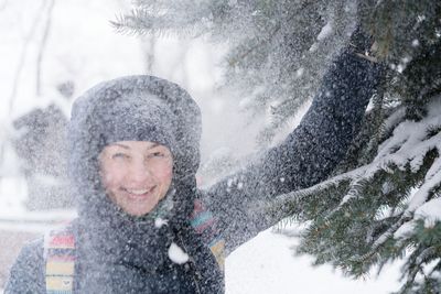 Portrait of smiling woman enjoying snowfall