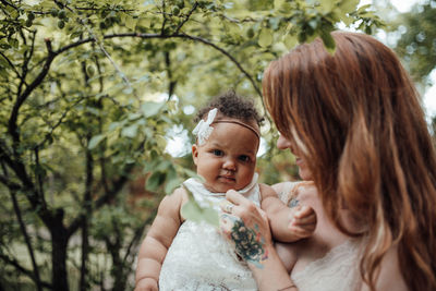 Portrait of mother and daughter against trees