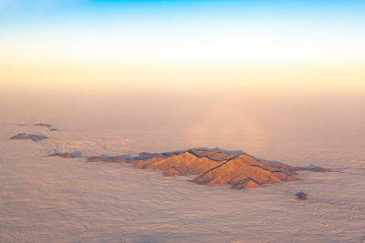 Aerial view of the top of a mountain rising above the clouds