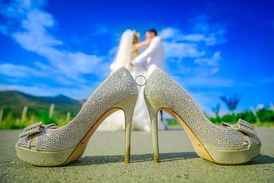 Low section of woman wearing high heels against blue sky