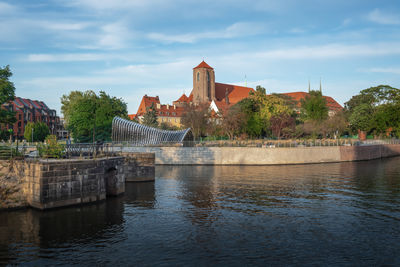 Buildings by river against sky