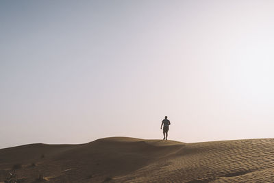 Man standing on landscape against clear sky