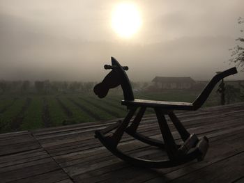 Rocking on horse on deck against sky during sunset