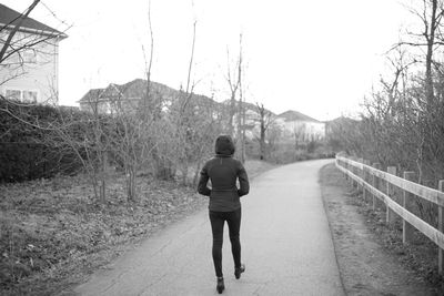 Rear view of woman walking on road against sky