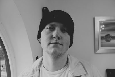 Close-up portrait of man wearing knit hat while standing by window