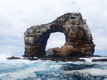 Rock formation in sea against sky