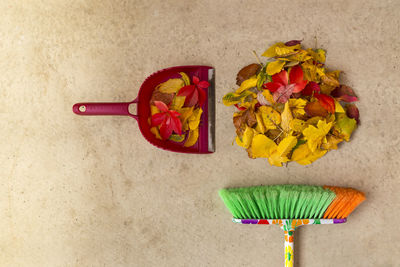 Directly above shot of broom with fallen autumn leaves on floor