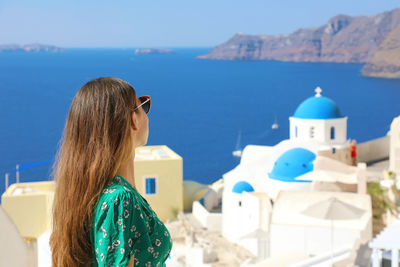 Side view of woman looking at houses and sea