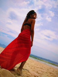 Full length of woman standing at beach against sky