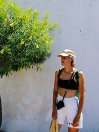 Portrait of young woman standing against wall